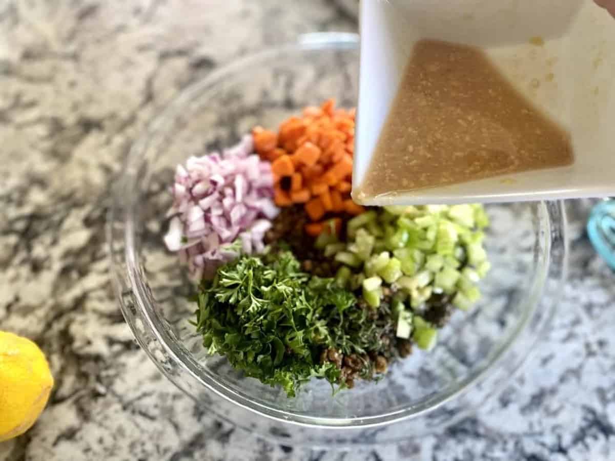 I am pouring salad dressing into a bowl of salad ingredients. 