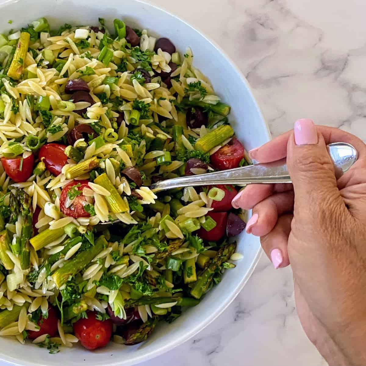 Asparagus Salad Recipe Asparagus salad in a bowl with a fork on the counter.