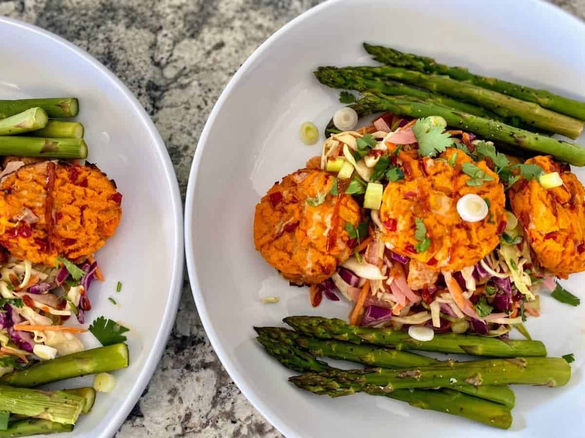 The recipe served with Asian coleslaw and asparagus in two large bowls on the table