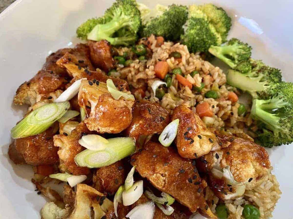 Simple Tso Cauliflower Recipe Simple tso cauliflower in a bowl with fried rice and broccoli