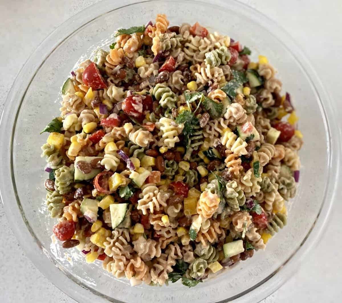 Mexican pasta salad tossed in a bowl with dressing. 