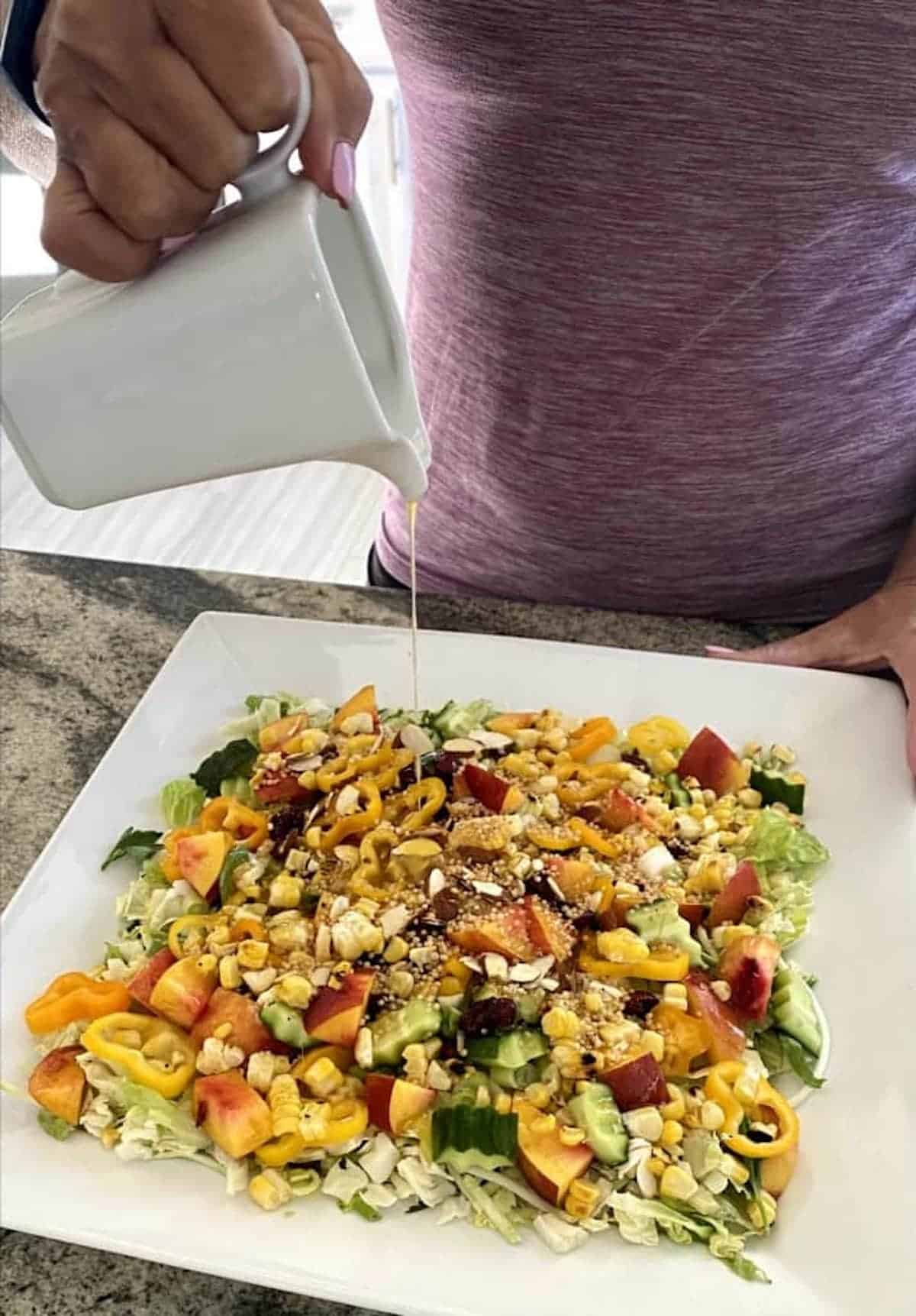 Pouring tangerine dressing on the nectarine salad recipe