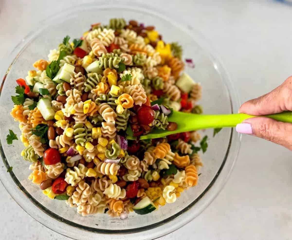 Tossing the ingredients together in a bowl on the table. 