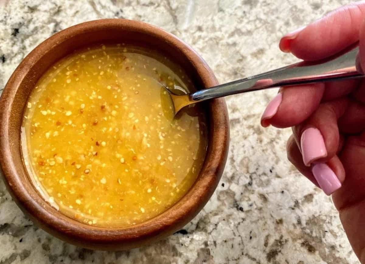 Citrus dressing in a bowl with a spoon in it.
