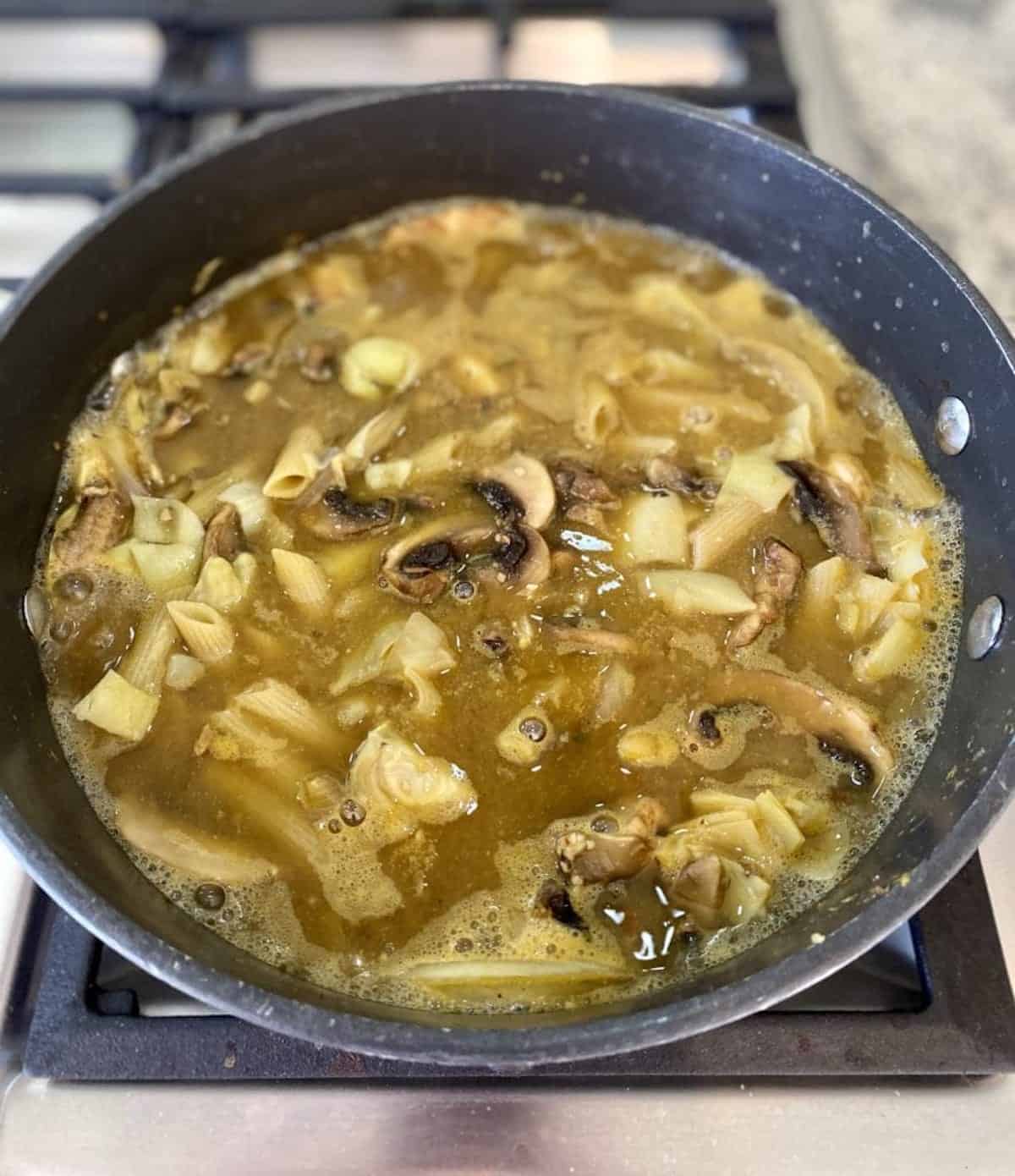 I am adding pasta and vegetable broth in a pot on the stove.