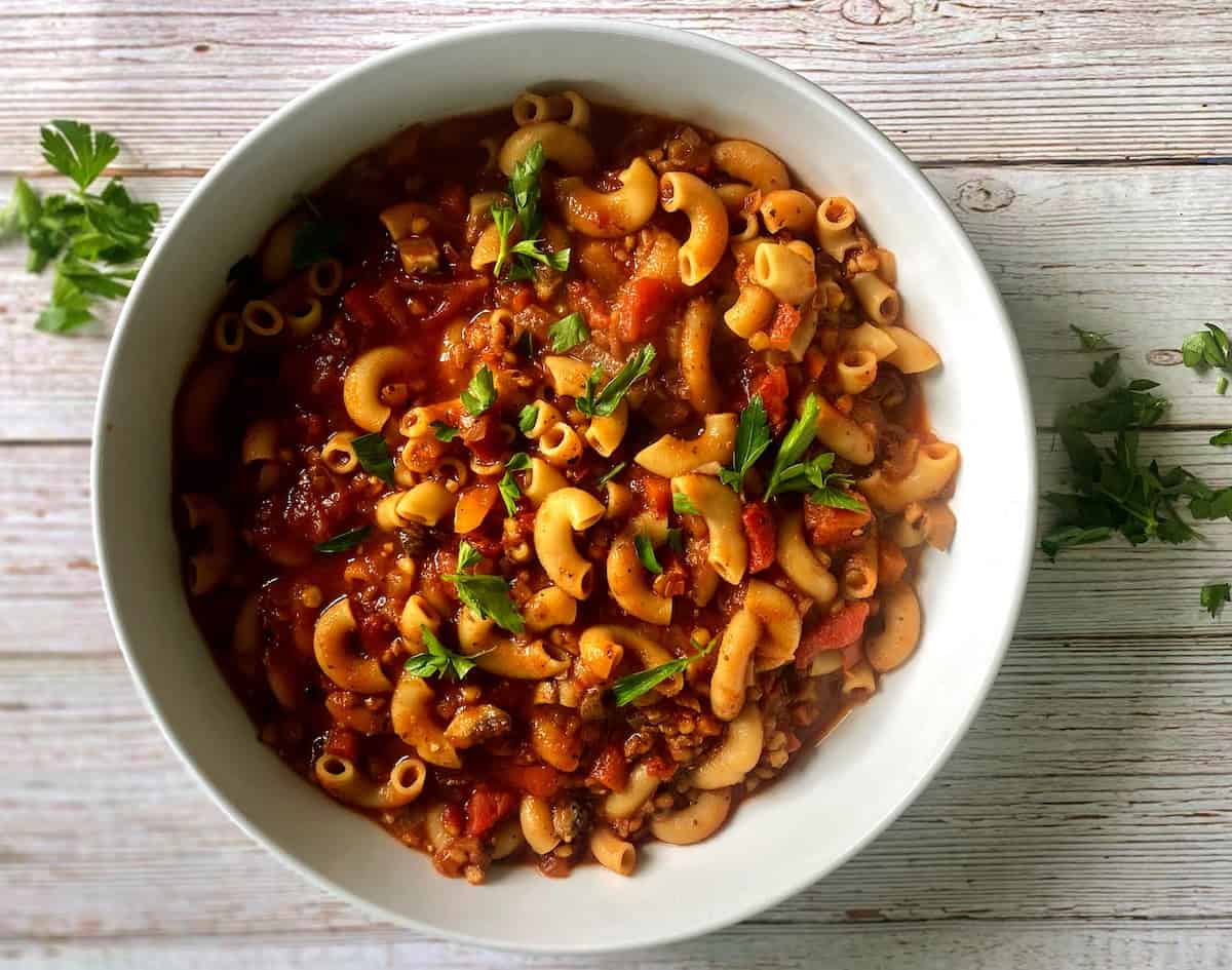 Vegan goulash in a bowl on the counter with parsley garnish.
