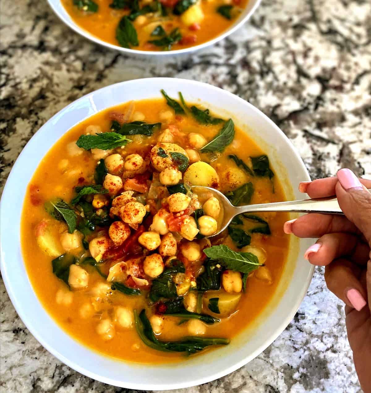 chickpea stew served in a bowl on the table with another bow of stew behind it. 