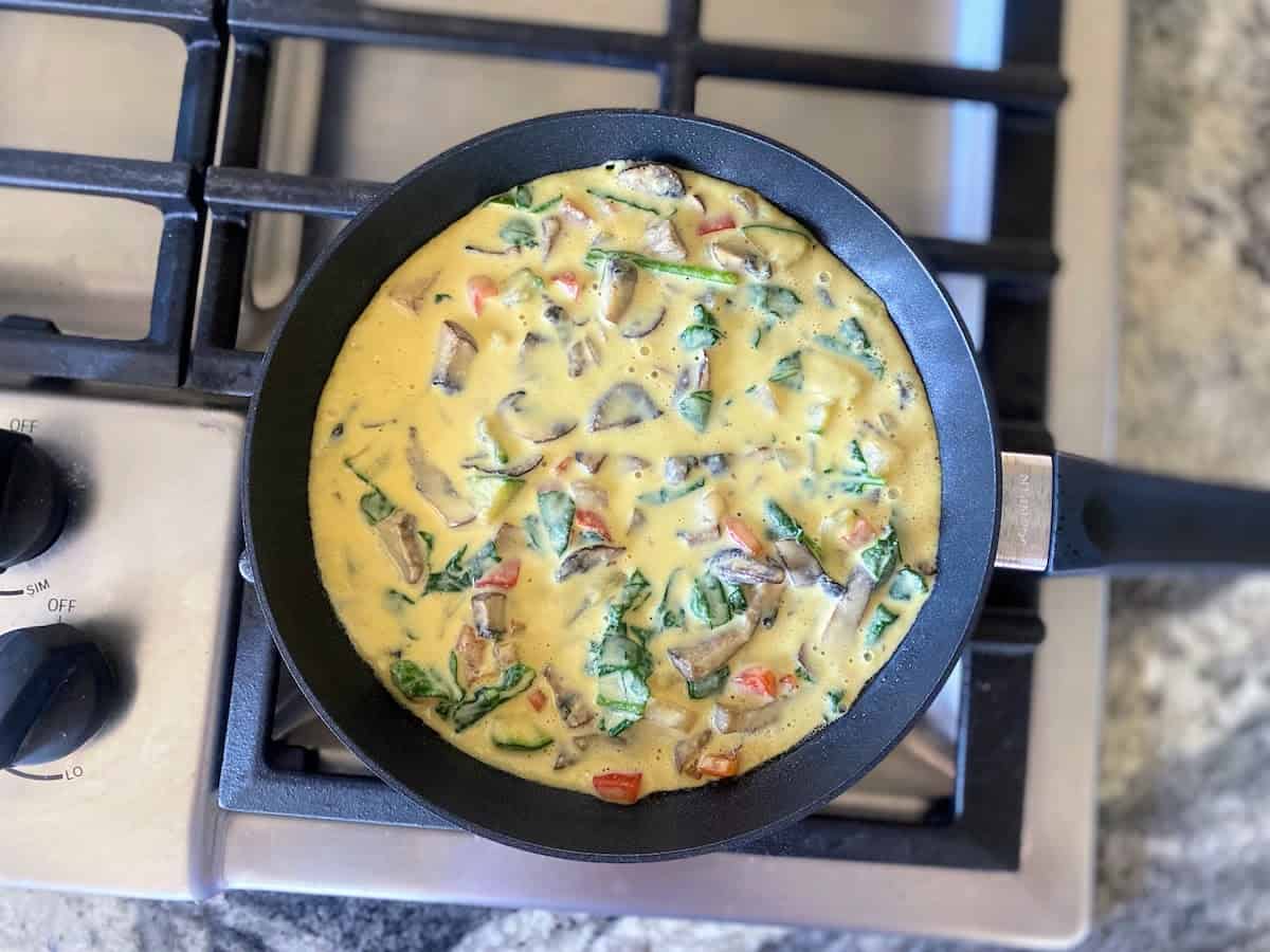 Just egg mixed with cooked vegetables in a pan on the stove