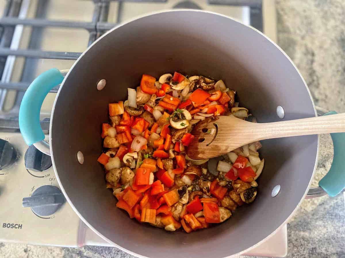 Add the peppers and mushrooms to the pot with the onions on the stove