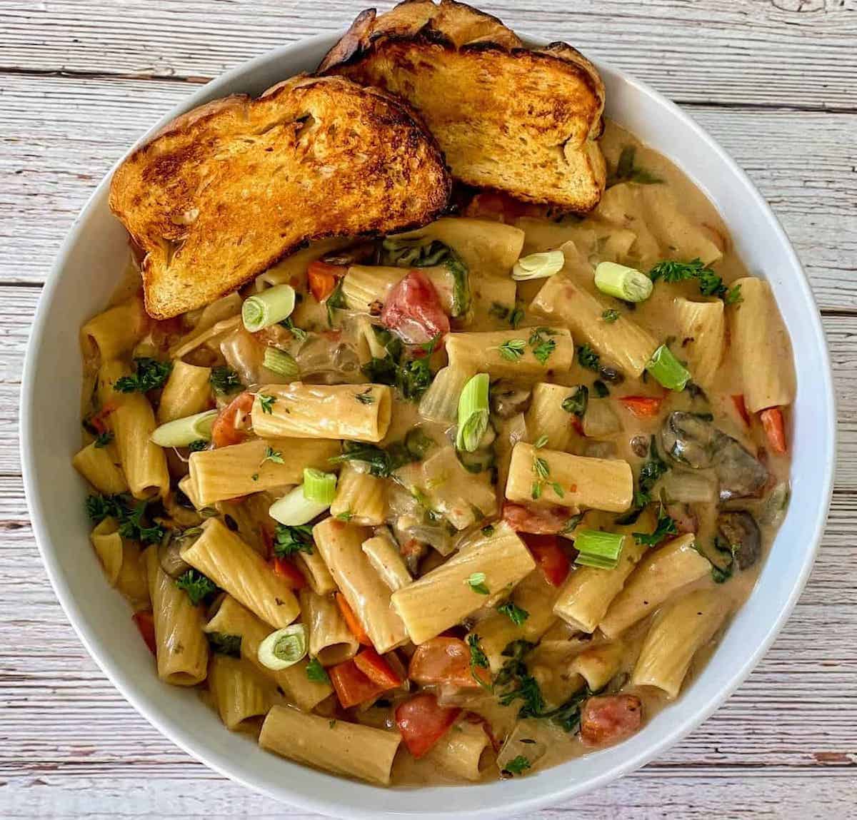 Cajun pasta served with sour dough bread in a bowl.