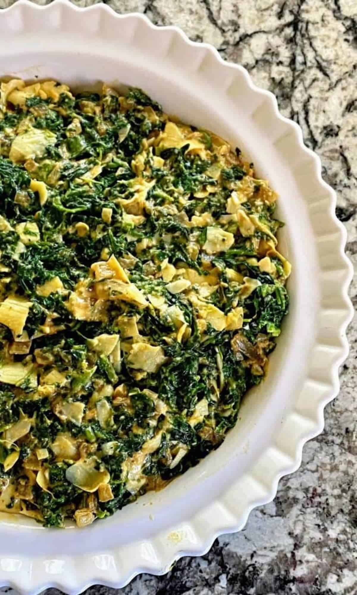 Vegan spinach artichoke dip in a pie pan on the counter.