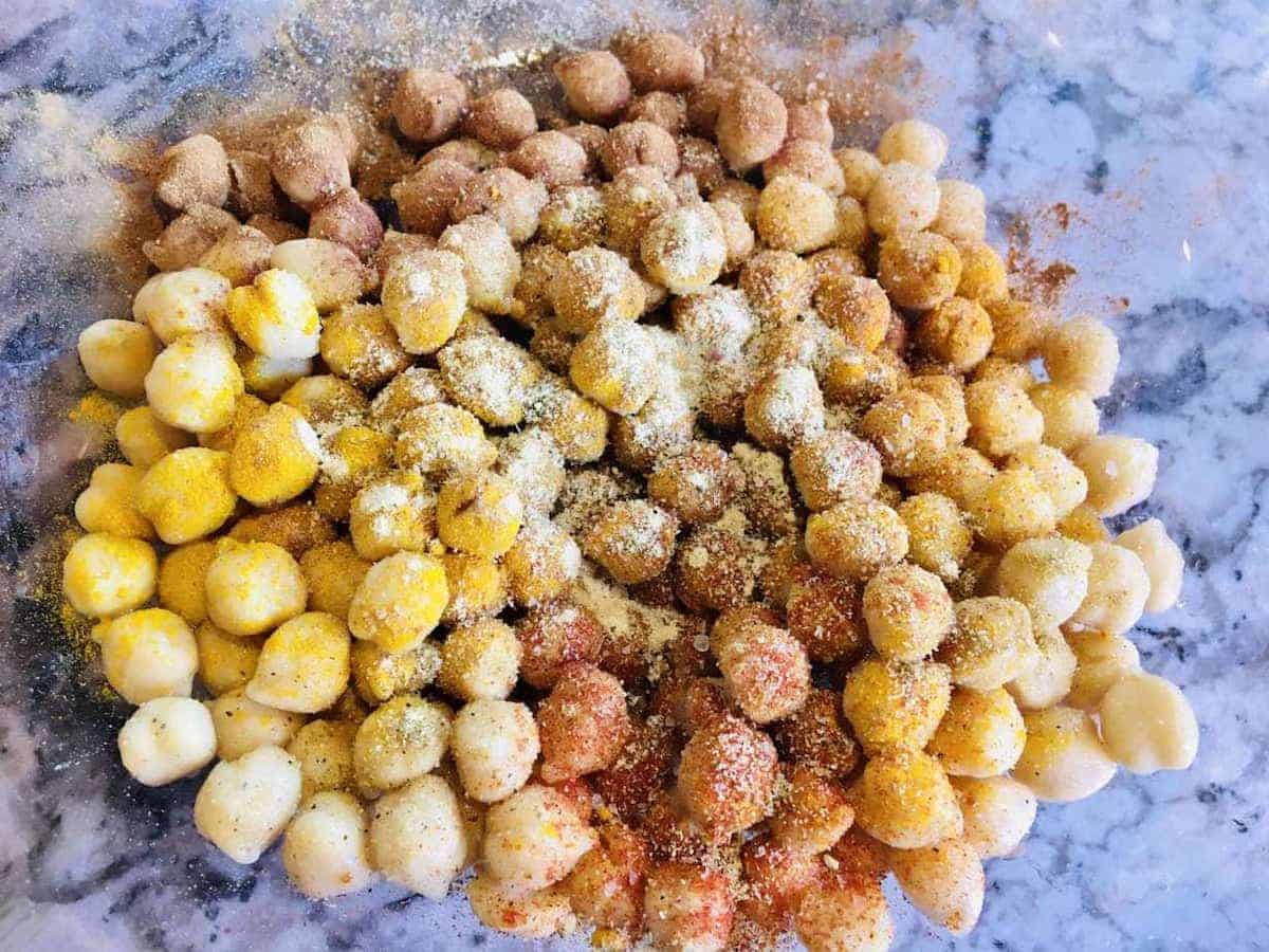 Chickpeas in a bowl with seasonings ready to be baked in the oven. 