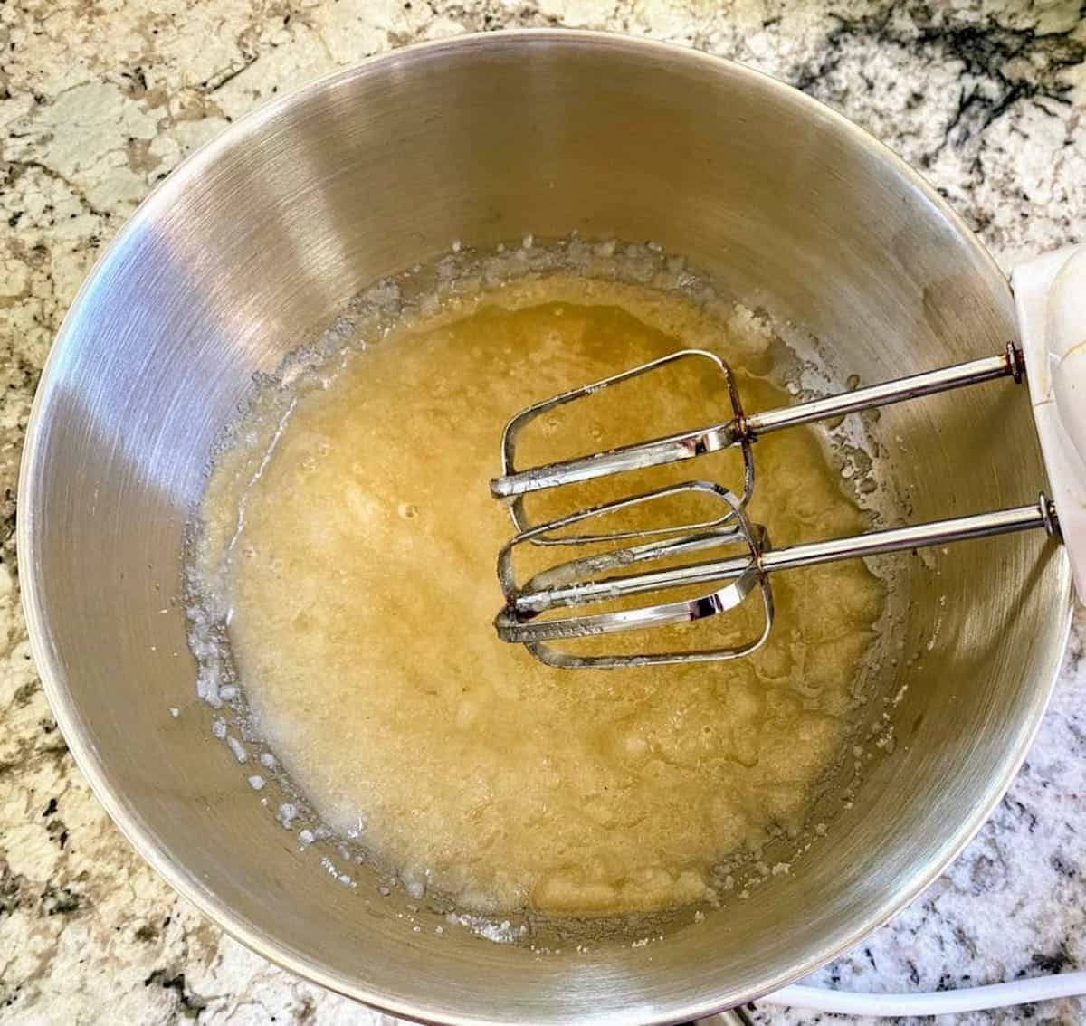 Creaming the vegan butter and applesauce with an electric mixer in a bowl.