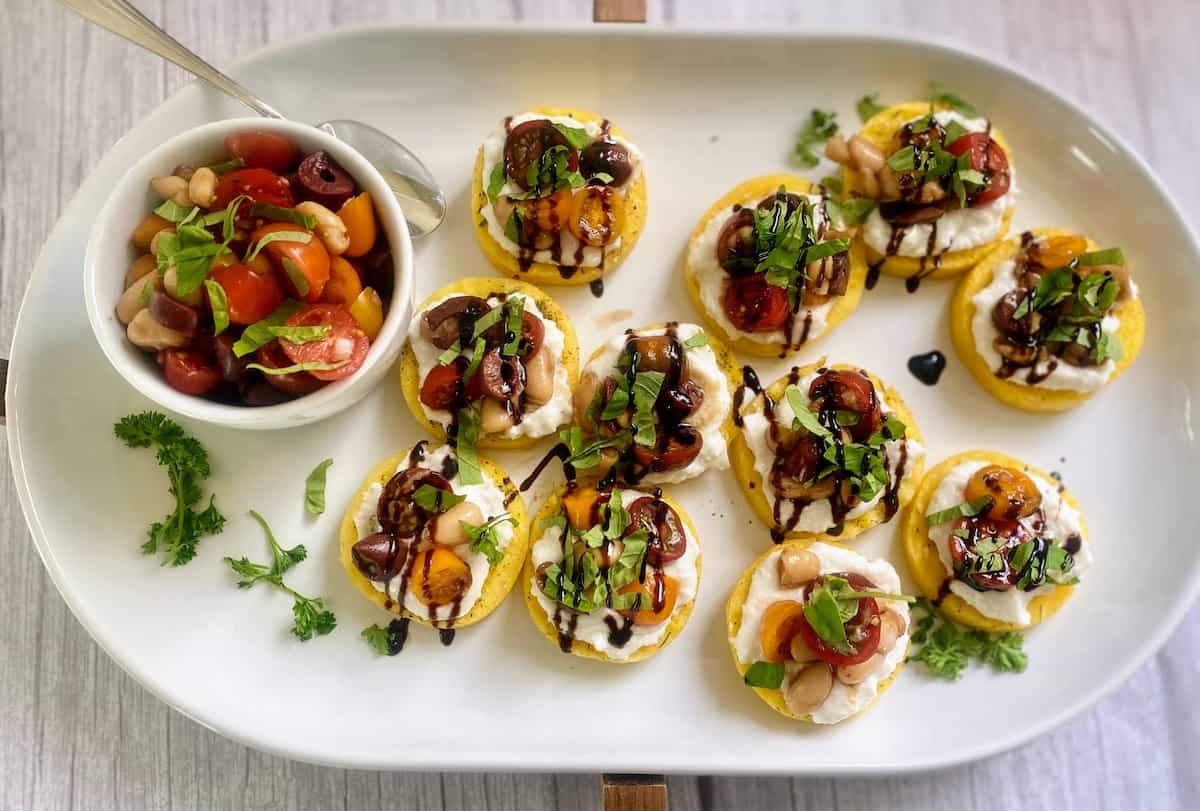 Prepared Mediterranean-topped cakes with a side of additional bruschetta topping. 
