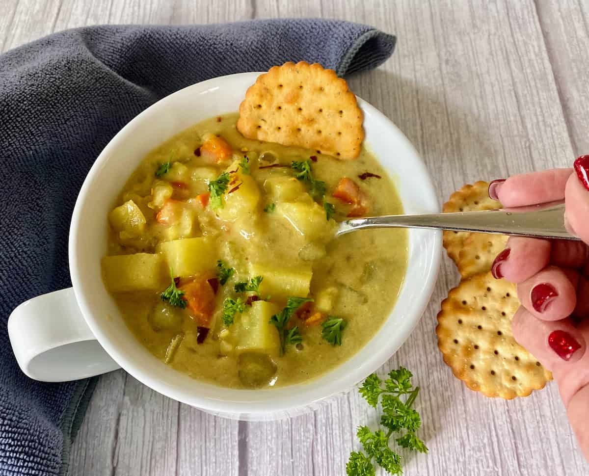 Potato chowder recipe in a bowl with a spoon with crackers.