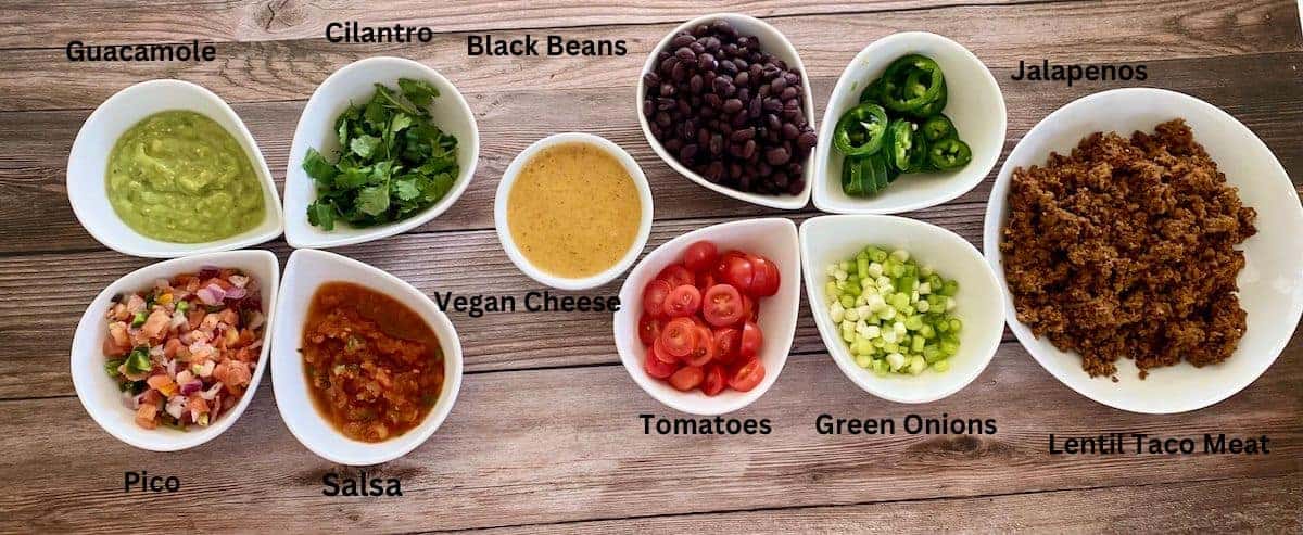 Cauliflower nacho ingredients: lentil taco meat, green onions, tomatoes, jalapenos, black beans, vegan nacho cheese sauce, salsa, cilantro, guacamole. And pico de gallo.