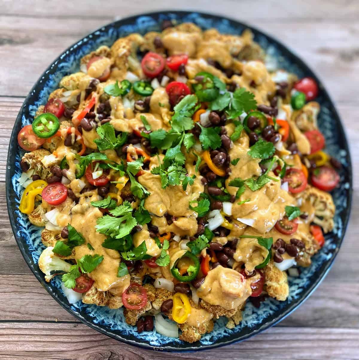 The cauliflower nachos recipe is served on the table garnished with cilantro.
