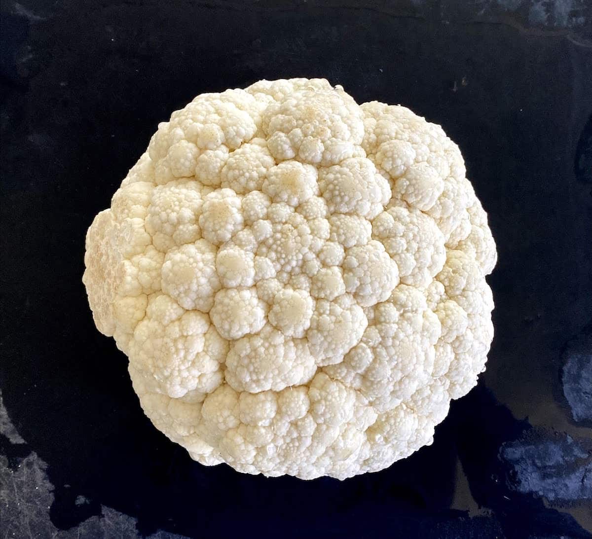 A head of cauliflower on a cutting board.