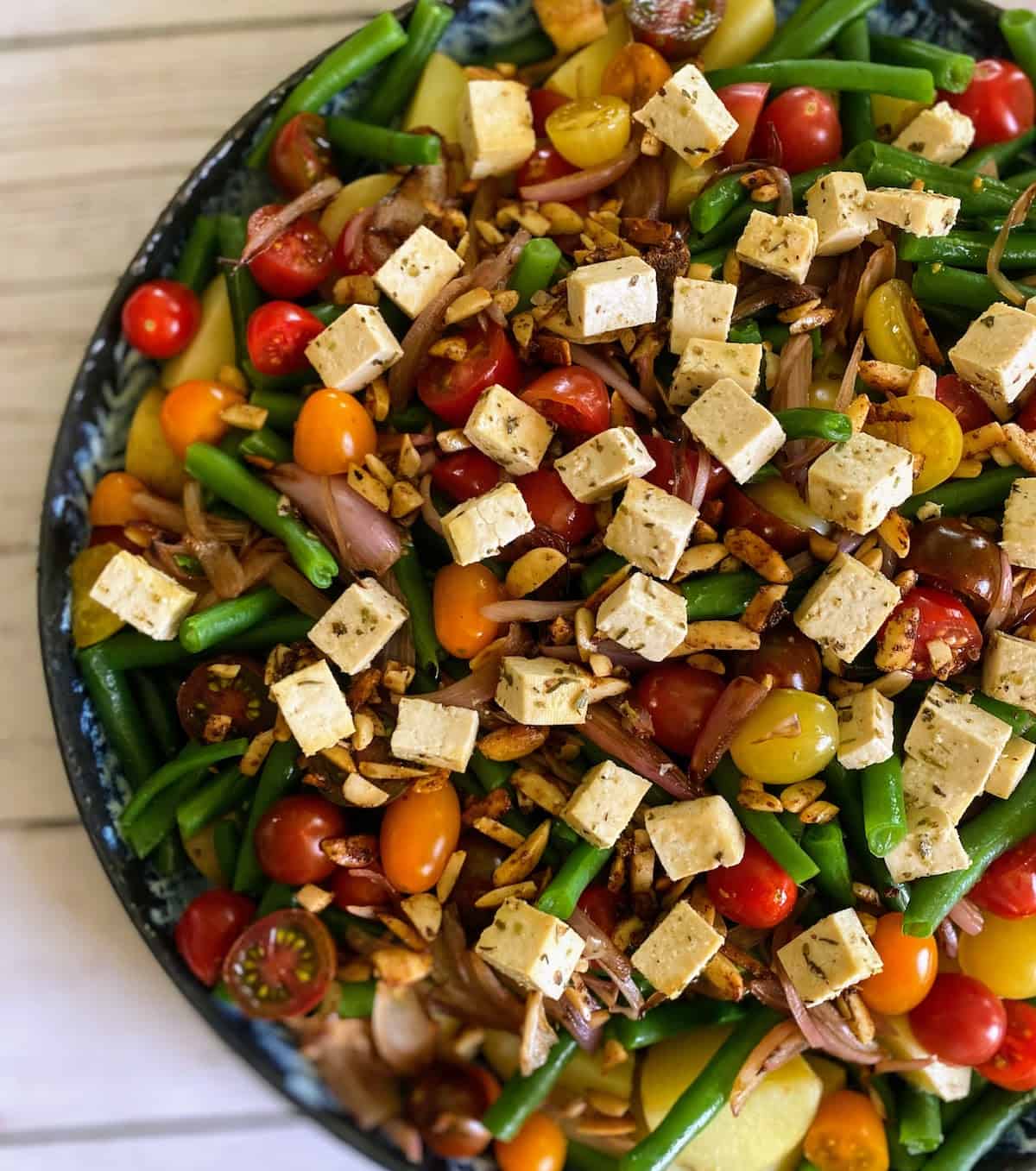 Green bean salad recipe with tofu feta cheese on a platter on the counter.