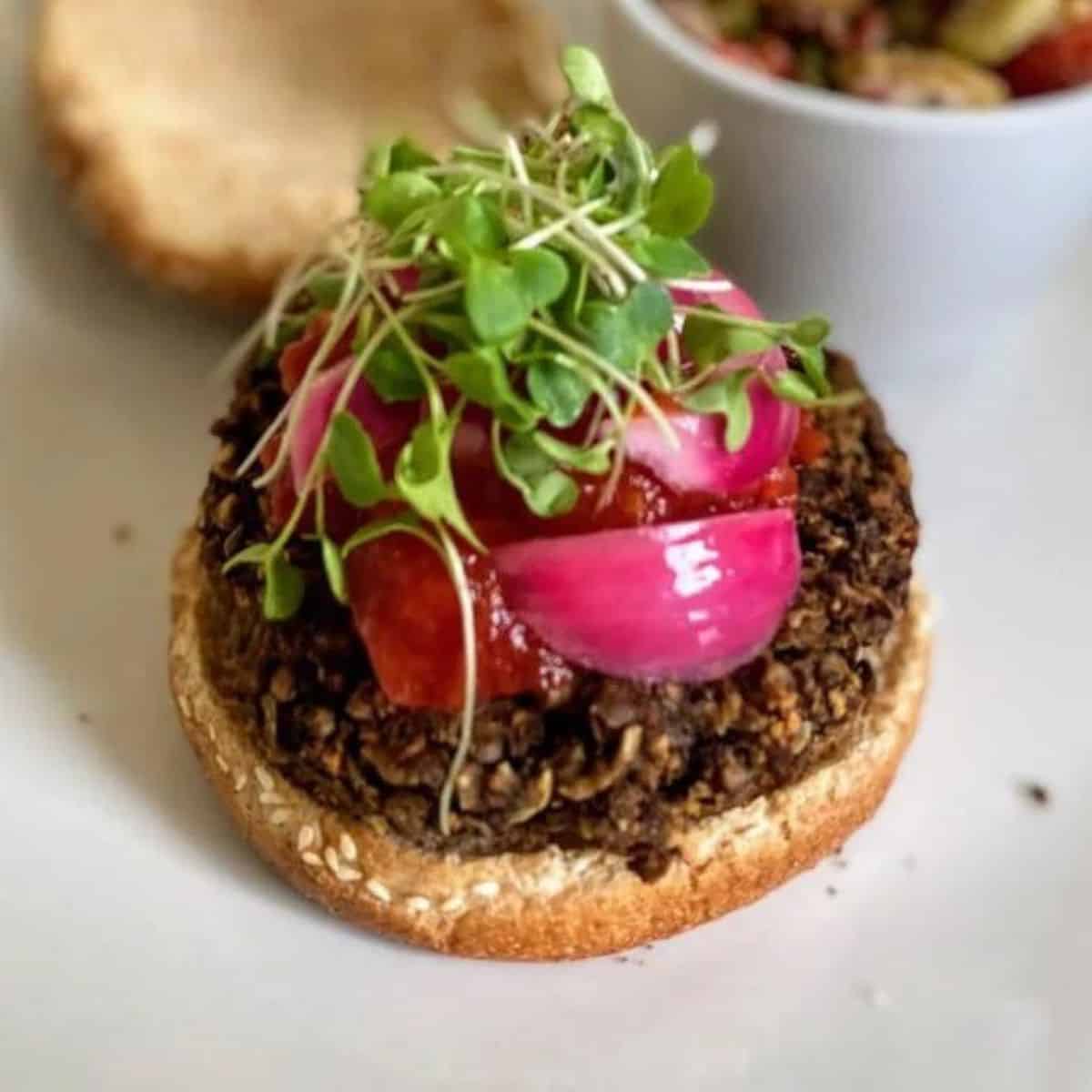 The recipe is served with tomato jam, pickled red onions, and microgreens.