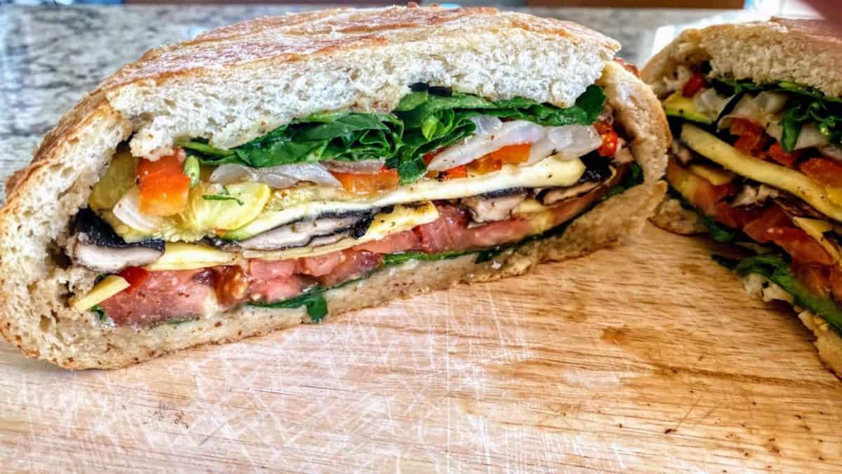 A vegan Muffuletta sandwich recipe cut into slices on a cutting board. 