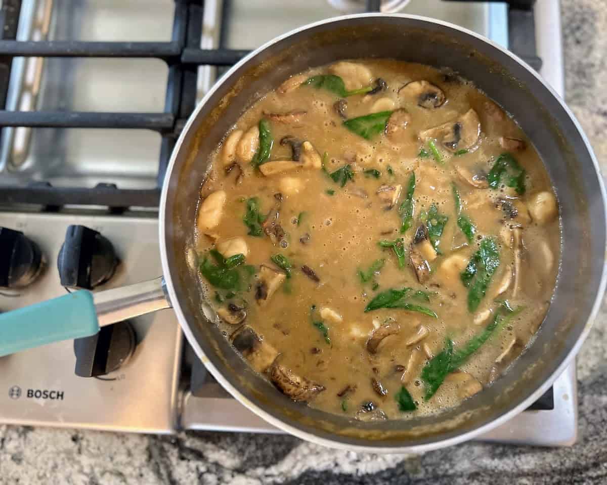 I added the vegetable broth, plant milk mixture, gnocchi, and spinach to the pan. 