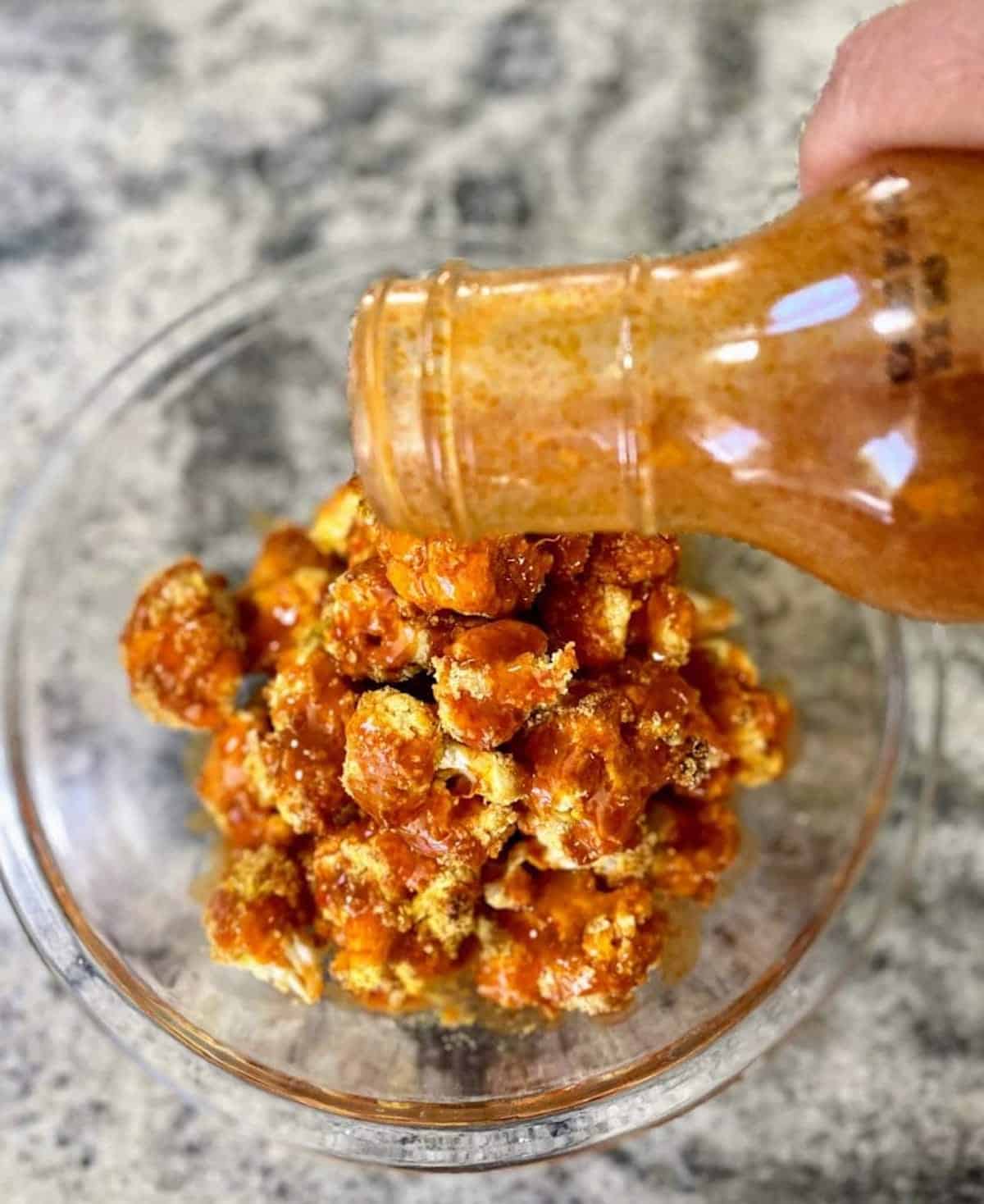 I am pouring buffalo sauce on the vegan wings.