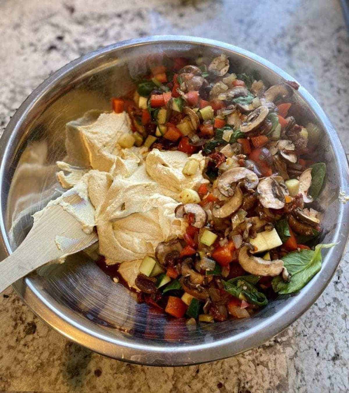 I am mixing the tofu mixture with the sautéed vegetables in a bowl. 