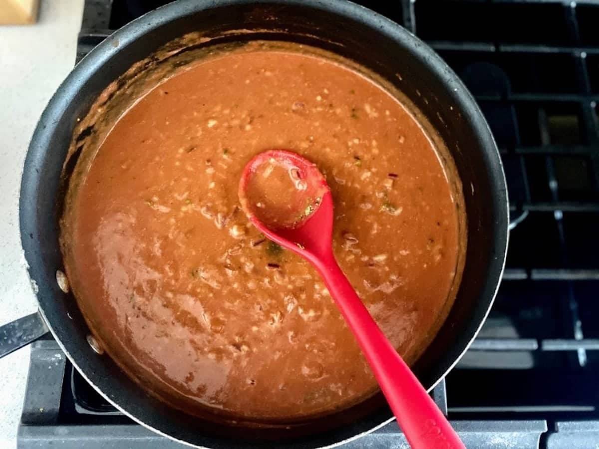 Rose pasta sauce in a pan on the stove with a spoon in the pan.