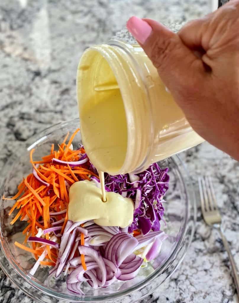 I am pouring classic vegan coleslaw dressing into the bowl.