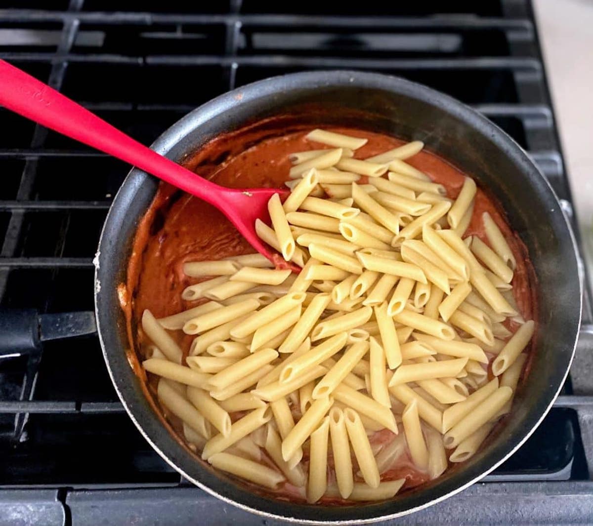 Add the cooked penne pasta to the pink pasta sauce.