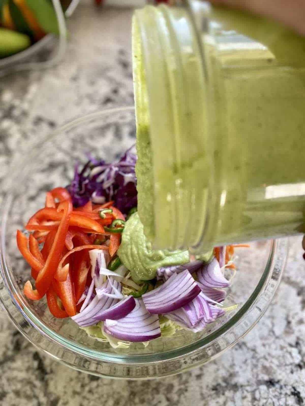 I am pouring avocado dressing into the recipe ingredients.