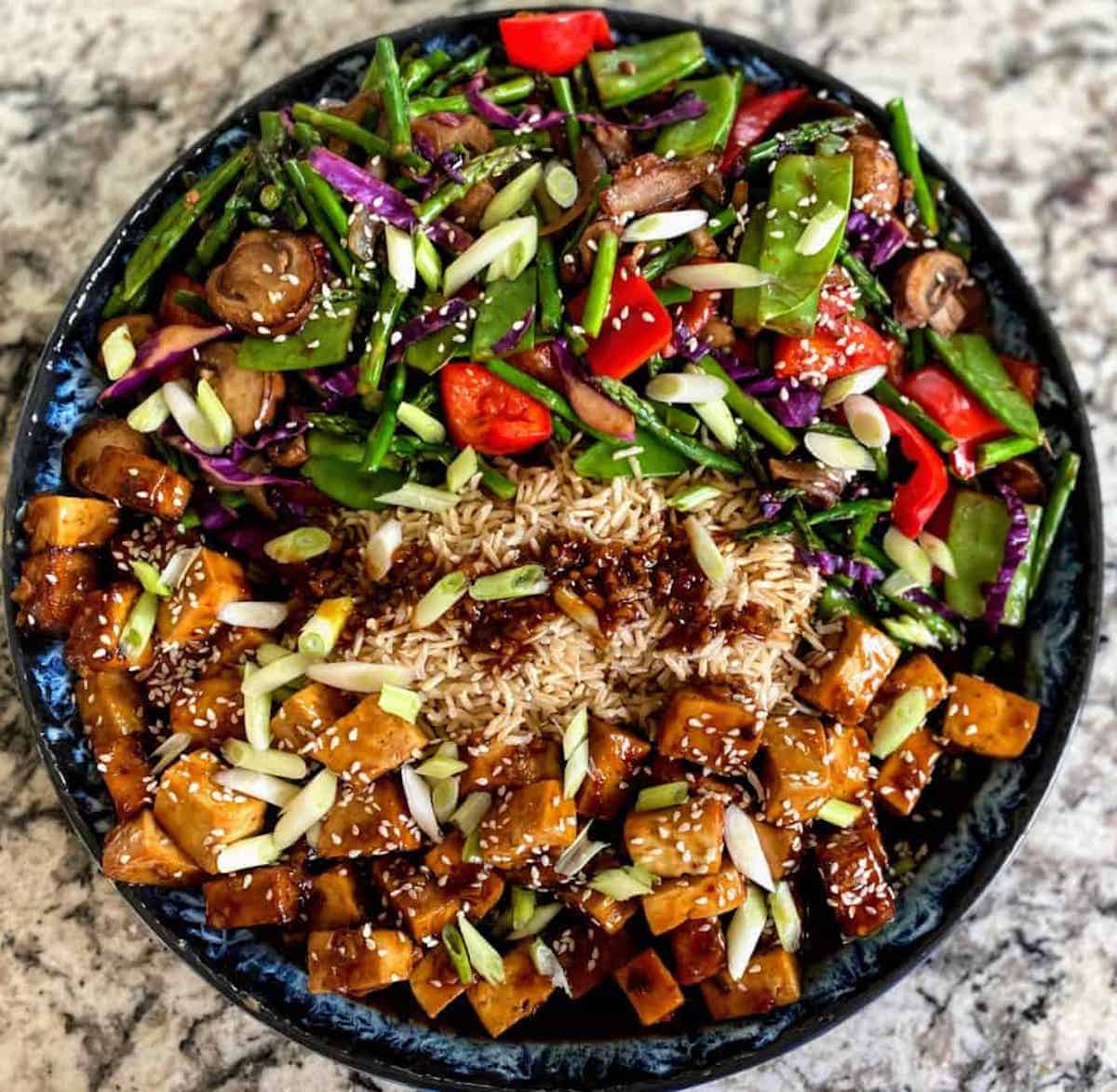 Vegan Kung Pao Tofu Recipes served with Kung Pao vegetables on a platter with brown rice and Kung Pao sauce. 