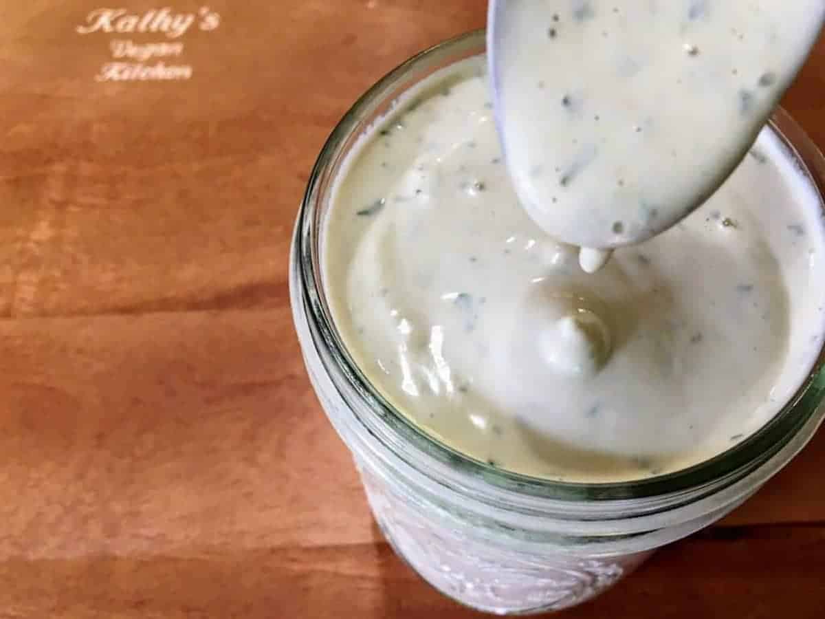 Ranch dressing in a ball jar with a spoon in it.
