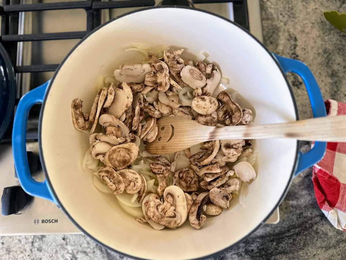 Mushroom, onions, garlic and ginger cooking in a Dutch oven on the stove. 